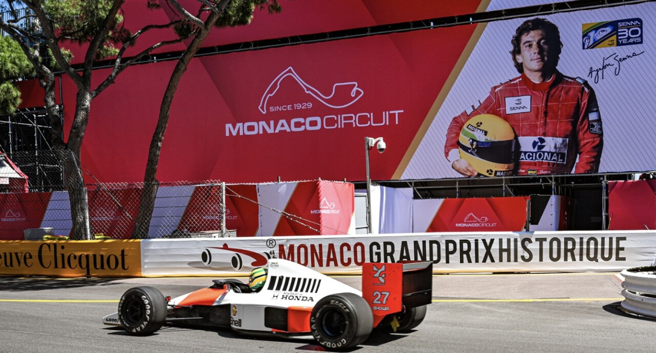 Homenagem a Ayrton Senna no circuito de Monte Carlo em 2024, com carro histórico da McLaren diante de painel comemorativo do legado do tricampeão